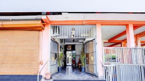 A building entrance with a staircase leading to a covered area, metal railings, and potted plants. - Saver Double Ruthran Guest House (Tirukalukundram)