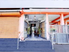 A building entrance with a staircase leading to a covered area, metal railings, and potted plants. - Saver Double Ruthran Guest House (Tirukalukundram)