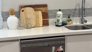 Una cocina con lavavajillas, tabla de cortar de madera y utensilios de cocina.