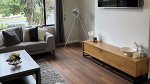 Una sala de estar moderna con un sofá, una mesa de centro, un televisor y un mueble bajo de madera.