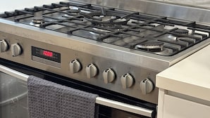 Una cocina con estufa, horno de acero inoxidable y salpicadero de azulejos.