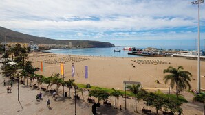 Une zone de plage côtière avec une promenade, des parasols de plage et des drapeaux.