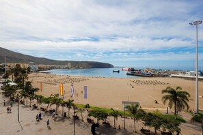 A coastal beach area with a promenade, beach umbrellas, and flags. - Luxury beachfront apartment in the heart of Los Cristianos (Arona)