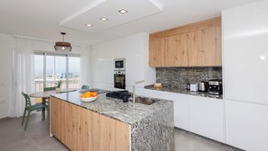 Une cuisine moderne dotée d’un îlot central, de meubles en bois et offrant une vue dégagée grâce à de grandes fenêtres.