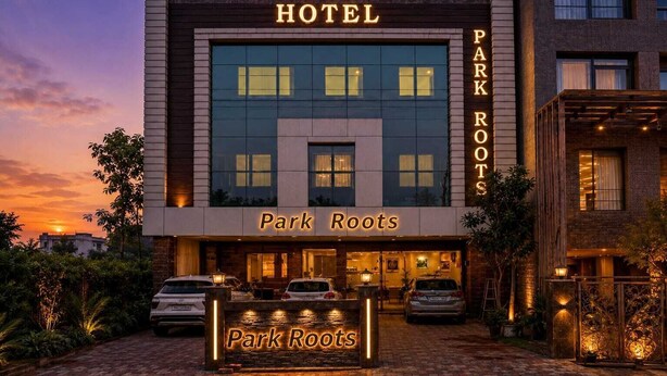 Un hôtel appelé « Park Roots », doté d’une façade moderne, d’une enseigne et d’un espace de stationnement.