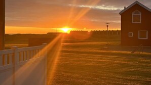 Un atardecer sobre un campo cubierto de hierba con un edificio y una cerca.