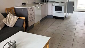 Una cocina moderna con comedor, que incluye una mesa con sillas, un sofá y una cafetera.