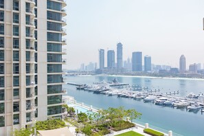 Un edificio de gran altura con un puerto deportivo y barcos al fondo.