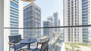 Een balkon met een ronde tafel en twee stoelen, met uitzicht op een stadsgezicht met wolkenkrabbers.