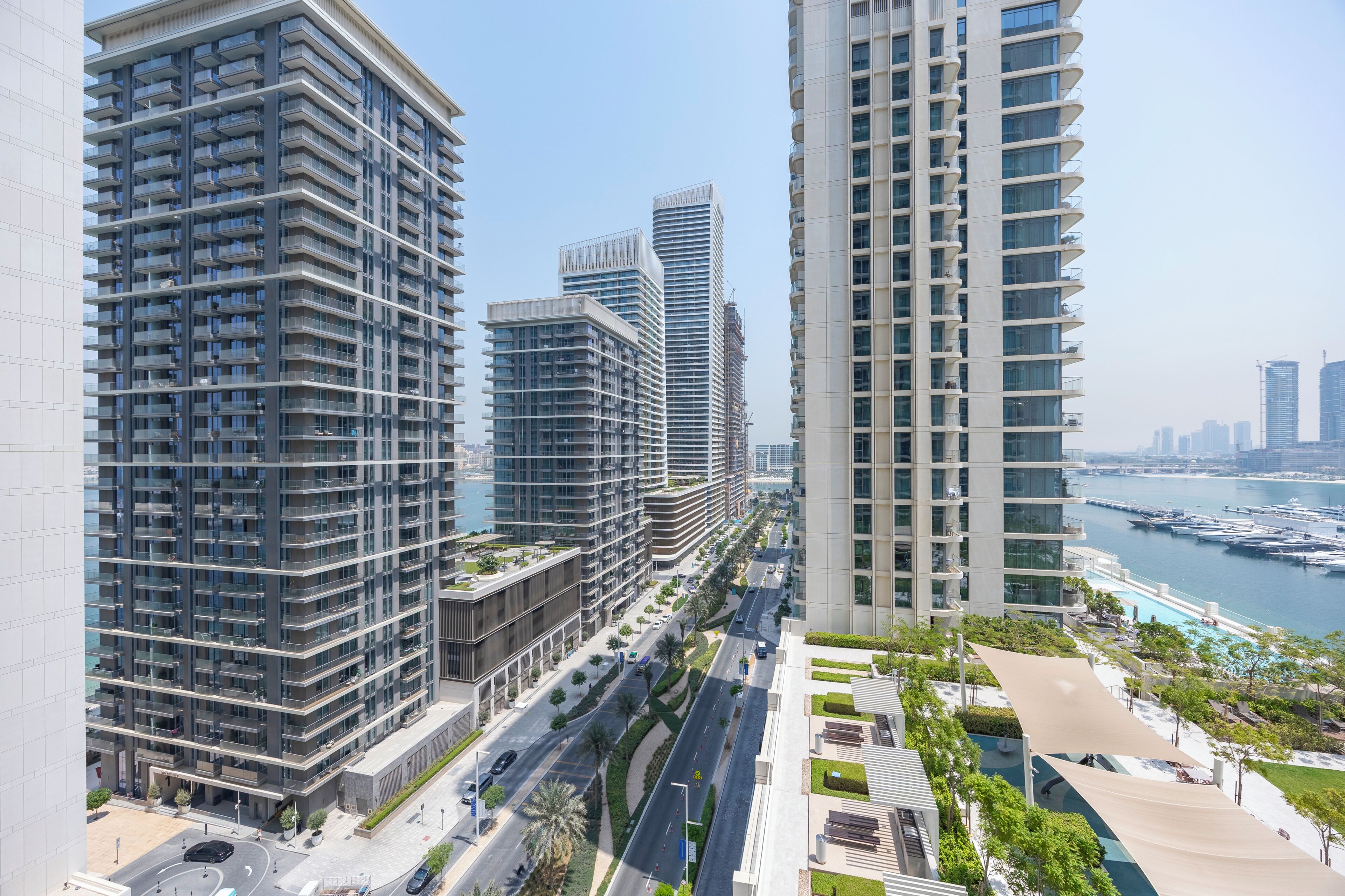 Un immeuble de grande hauteur doté de nombreux balcons, offrant une vue sur le front de mer et donnant sur une rue urbaine bien entretenue.