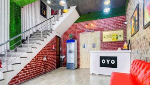 A reception area with a staircase, a reception desk labeled 'OYO,' and a red couch. - Saver Double Hotel R1 Inn (Jalandhar)