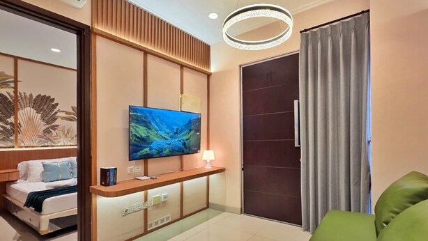 Una habitación de hotel moderna con televisión de pantalla plana, una mesita de noche, un sofá, una puerta corredera y un aplique de techo.