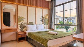 Habitación de hotel con una cama grande, un escritorio con espejo, un ventanal con vistas a edificios e iluminación empotrada en el techo.