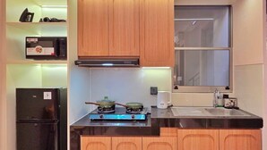 Una cocina compacta con armarios de madera, un refrigerador negro, una estufa a gas y un microondas.