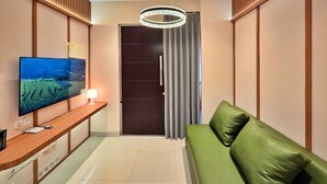 Una sala de estar moderna con televisor de pantalla plana, mesa consola de madera, sofá verde, lámpara de techo y puerta corrediza.