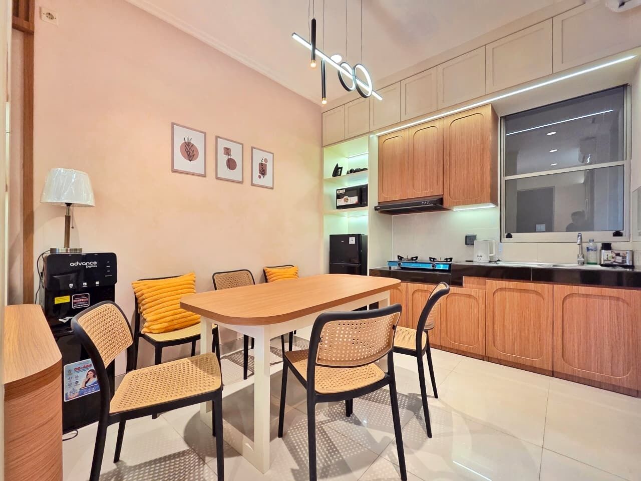 Una cocina moderna con armarios de madera, una mesa de comedor con sillas, una cafetera y una ventana.
