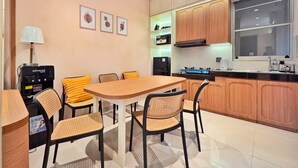 Una cocina moderna con armarios de madera, una mesa de comedor con sillas, una cafetera y una ventana.