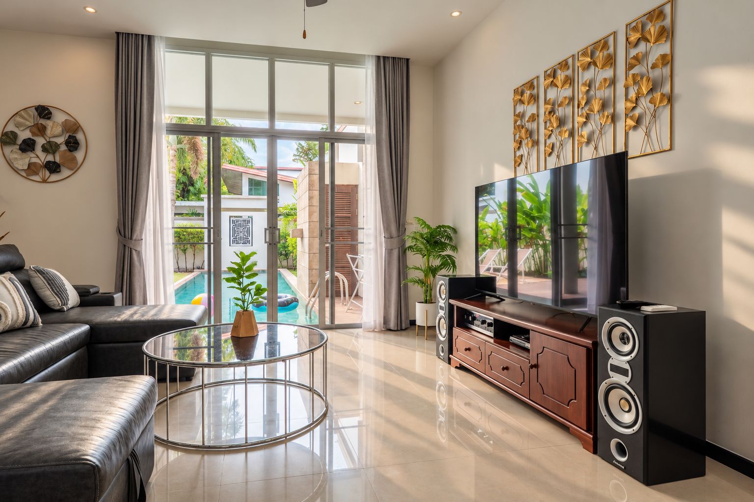 A modern living room with a glass coffee table, a sofa, a TV, and a speaker system.
