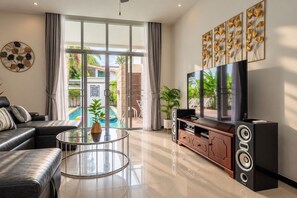 Una sala de estar moderna con una mesa de centro de vidrio, un sofá, un televisor y un sistema de sonido.