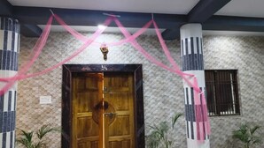 A wooden door with a decorative handle, flanked by columns with vertical stripes, and a window with bars. - Acharya Residency (Puri)