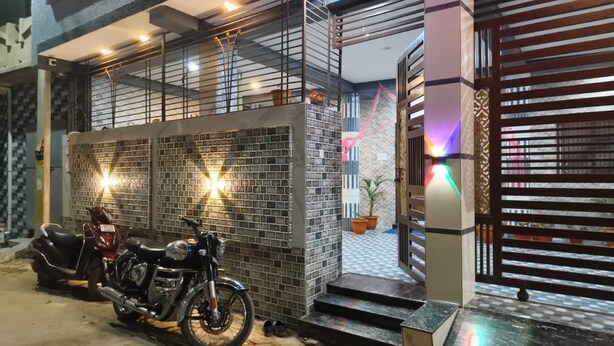 A motorcycle parked in front of a building with a tiled facade and a gated entrance. - Acharya Residency (Puri)