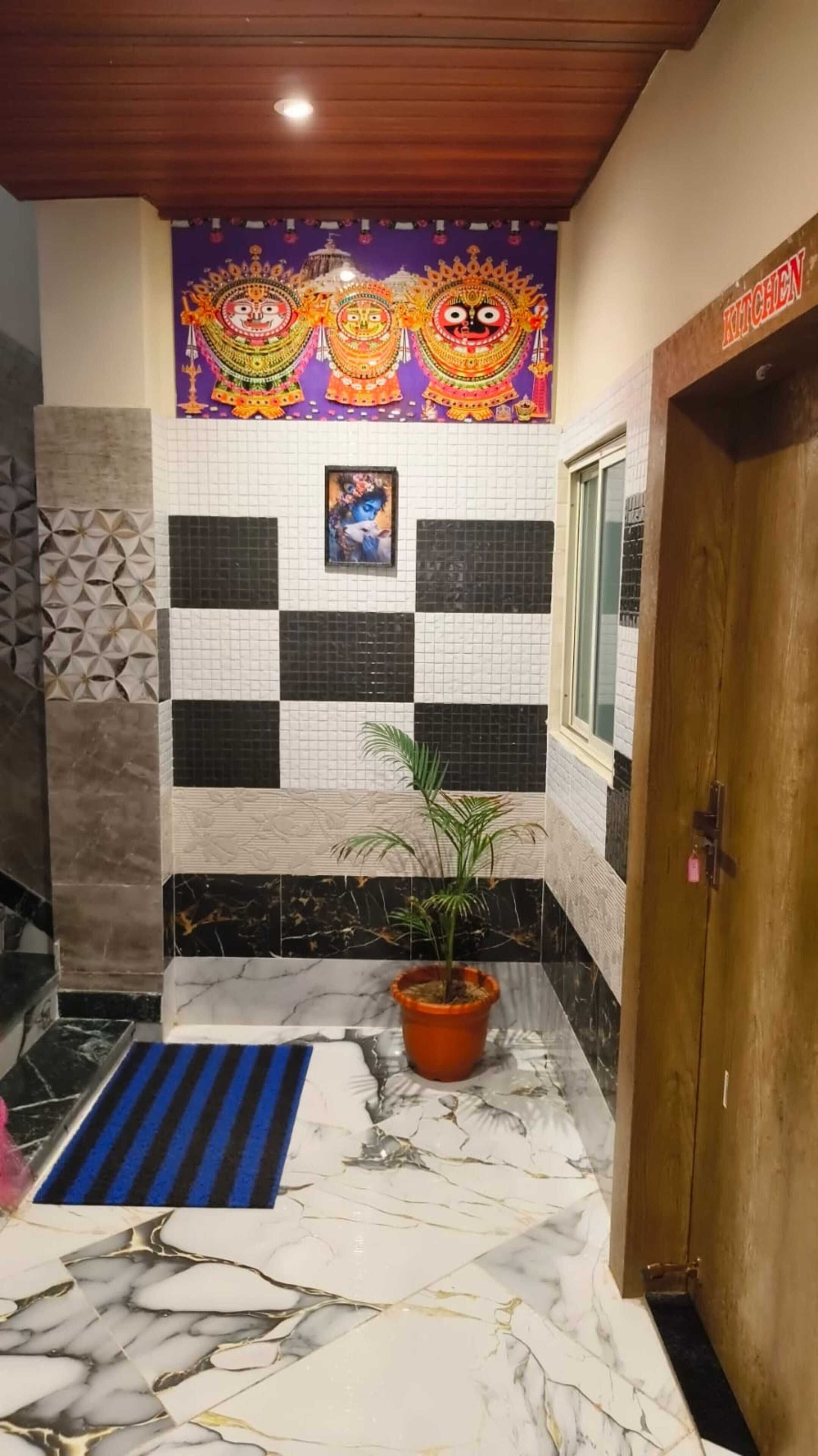 A bathroom with a checkered tile wall, a potted plant, a blue mat, and a wooden door.