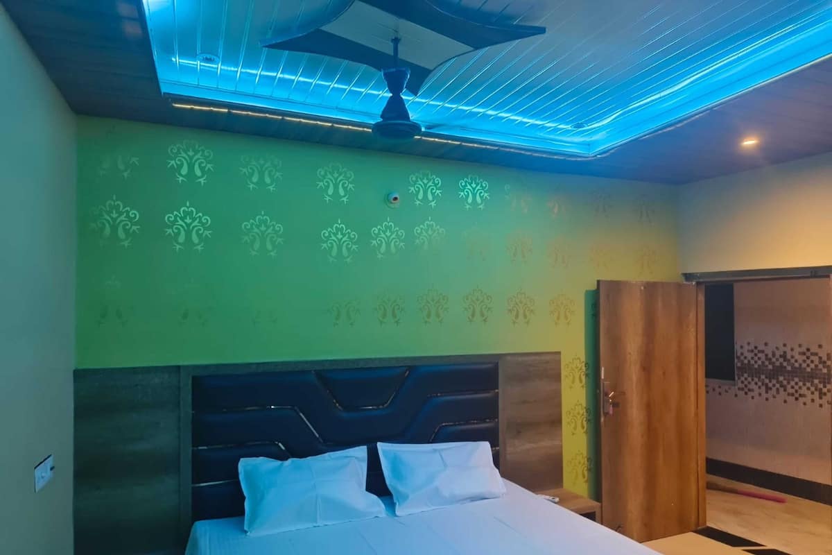 Quarto com cama, ventoinha no teto e parede estampada.