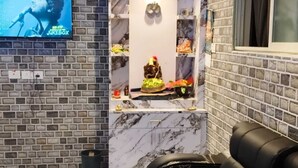 A room with a TV, massage chairs, a small shrine, and a marble floor. - Acharya Residency (Puri)