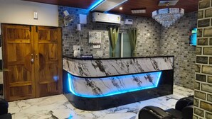 A reception desk with a marble top, a reception sign, a chandelier, and a brick wall. - Acharya Residency (Puri)