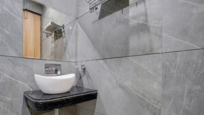 A bathroom with a white vessel sink, a wooden door, and a mirror. - Suite Hotel Midway (Amritsar)