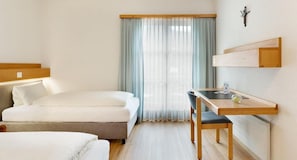 Una habitación de hotel con cama, escritorio y ventana con cortinas.