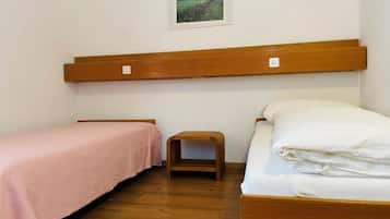 A bedroom with two beds, a wooden headboard, a small wooden stool, and a framed picture on the wall.