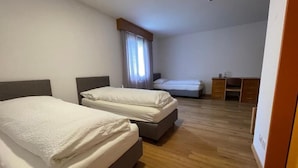 A hotel room with two beds, a desk, and a chair.