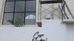 Fachada de edificio con un gran ventanal arqueado y un letrero que dice 'Casa Madre!'.