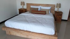 Una cama con estructura de madera, ropa de cama blanca y dos mesitas de noche con lámparas.