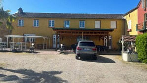 Un bâtiment jaune doté d’un patio couvert et d’un espace extérieur aménagé pour s’asseoir.