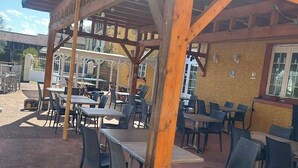 Une terrasse extérieure avec des poutres en bois, des tables et des chaises.