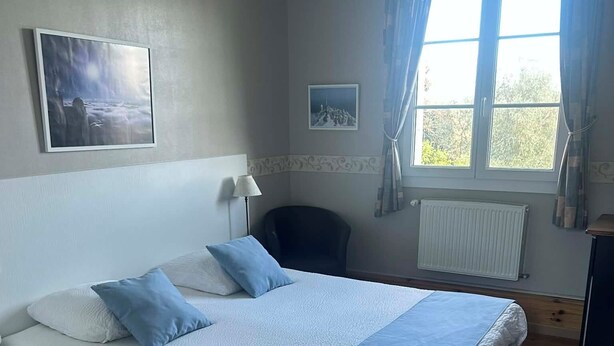 Une chambre à coucher avec un lit, une chaise, un bureau et une fenêtre avec des rideaux.