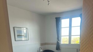 Une chambre avec deux lits, une table de chevet, un tableau encadré et une fenêtre avec des rideaux.