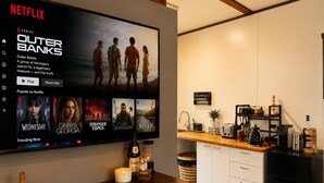 A modern kitchen with a flat-screen TV displaying a Netflix series.