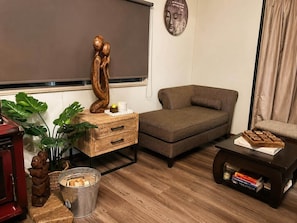 A cozy living room with a sofa, a wooden side table, a small coffee table, and a potted plant.