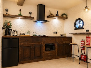 A kitchen with wooden cabinets, a black refrigerator, a stove, and a window.