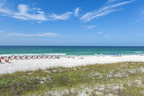 A beach with white sand, clear blue water, and red umbrellas. - Unwind Poolside, Walk to Shore! Miramar Beach Gem (Miramar Beach)