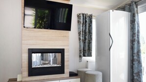 Ein modernes Wohnzimmer mit Kamin, Flachbildfernseher, weißem Heizkörper und weißem Kleiderschrank.