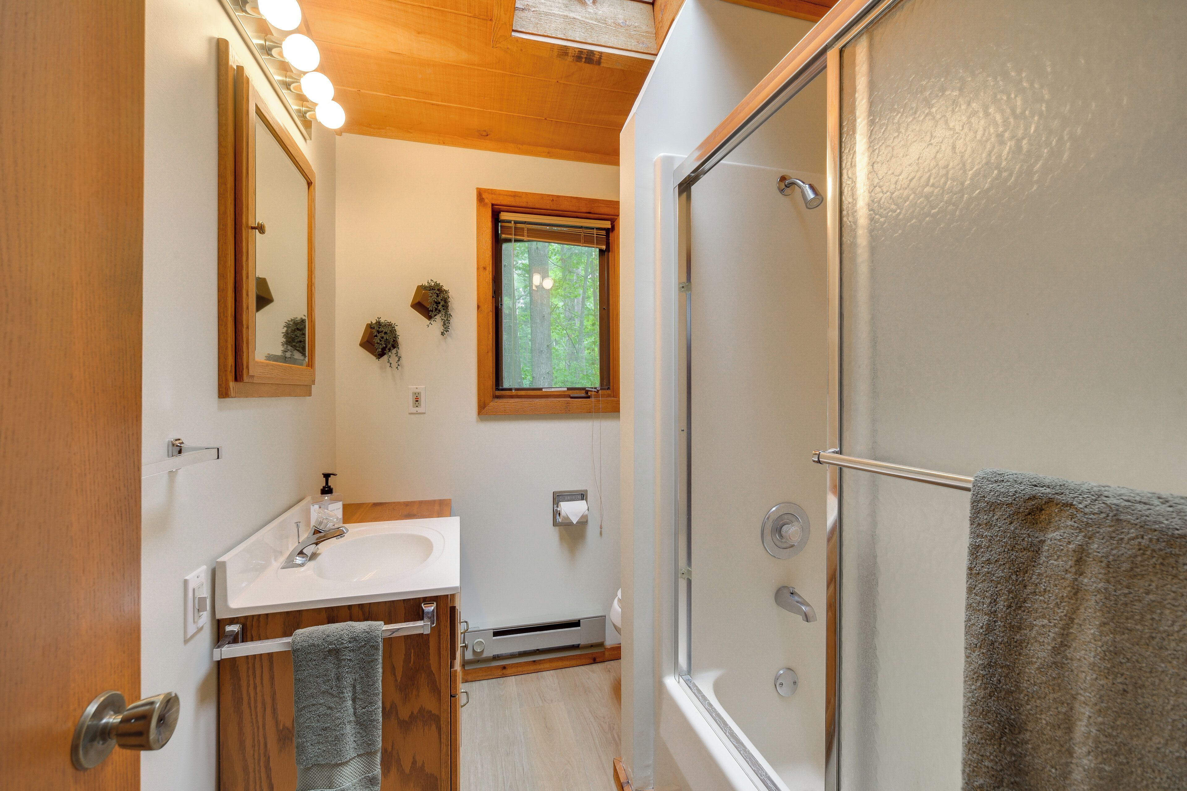A bathroom with a shower, sink, mirror, and towel rack.