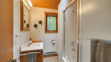 A bathroom with a shower, sink, mirror, and towel rack.
