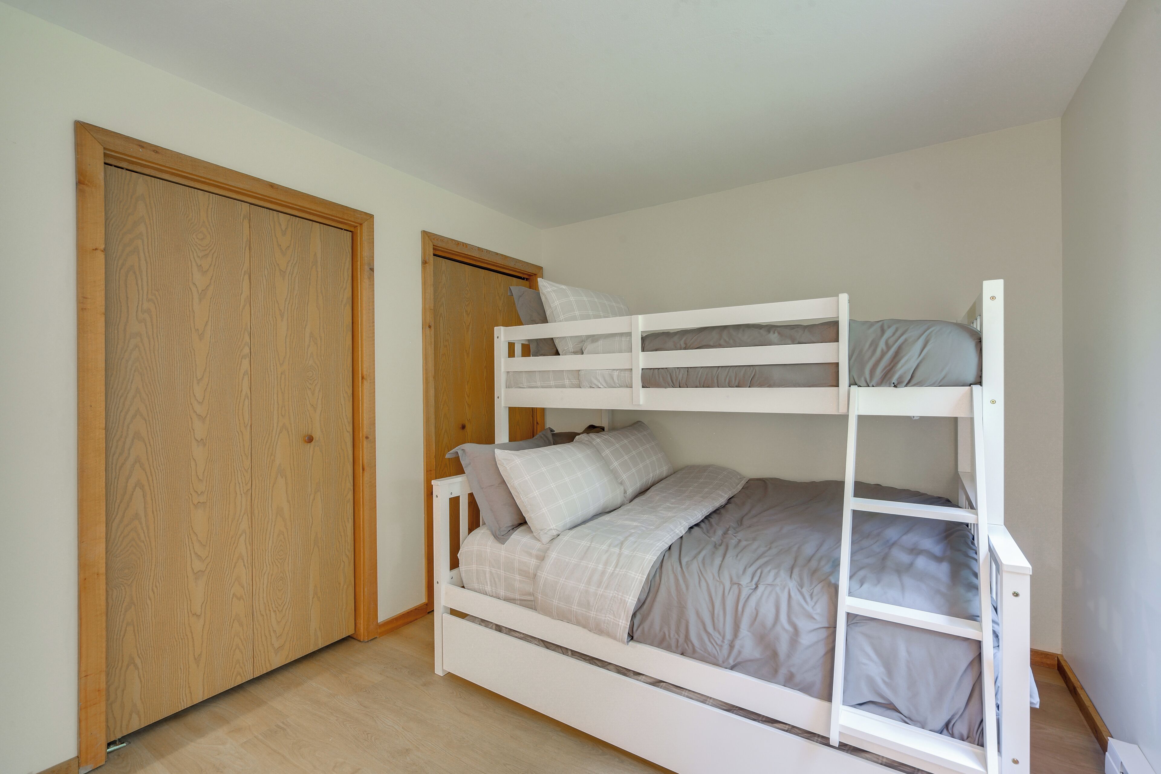 A bunk bed with a wooden wardrobe and a door in a bedroom.