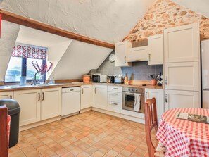 A kitchen with white cabinets, a wooden countertop, a microwave, a toaster, and a clock on the wall. - 2 bedroom accommodation in Dulverton (Dulverton)