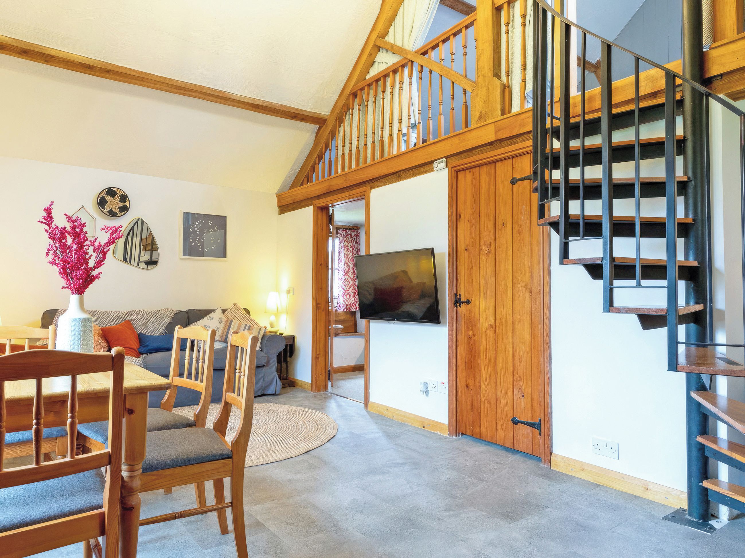 A living room with a wooden staircase, a sofa, a dining table, and chairs.