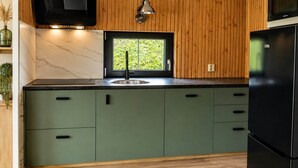Une cuisine avec des lambris en bois, un téléviseur noir, une fenêtre et un réfrigérateur noir.